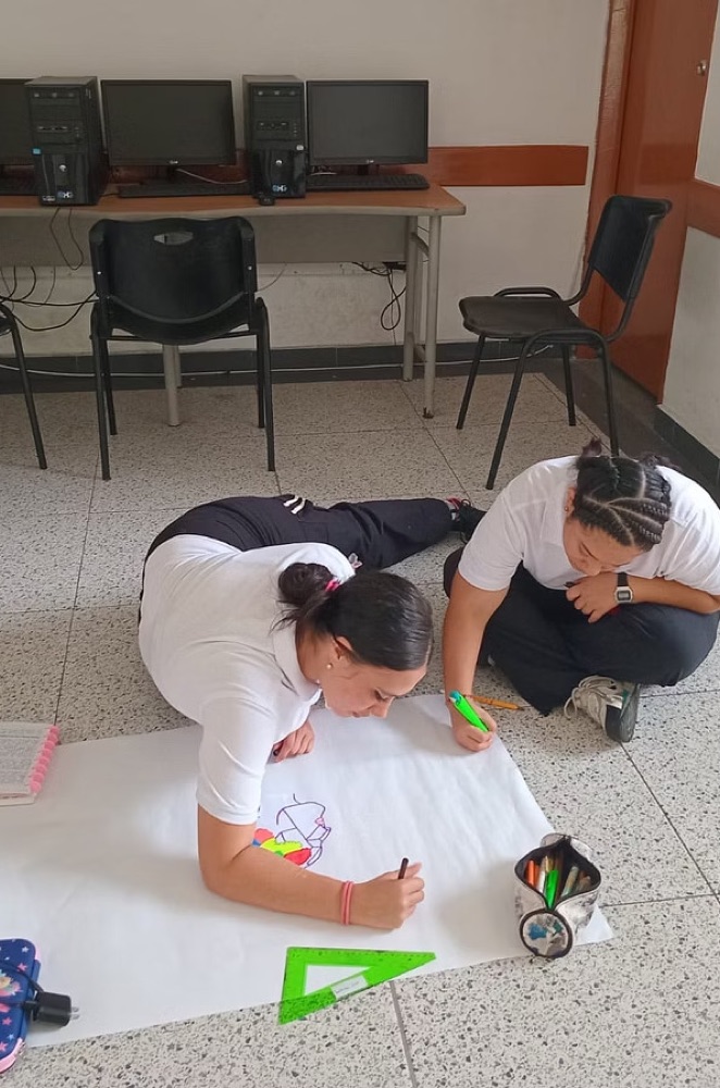 Dos mujeres del programa trabajando juntas en un taller sobre un pliego de papel